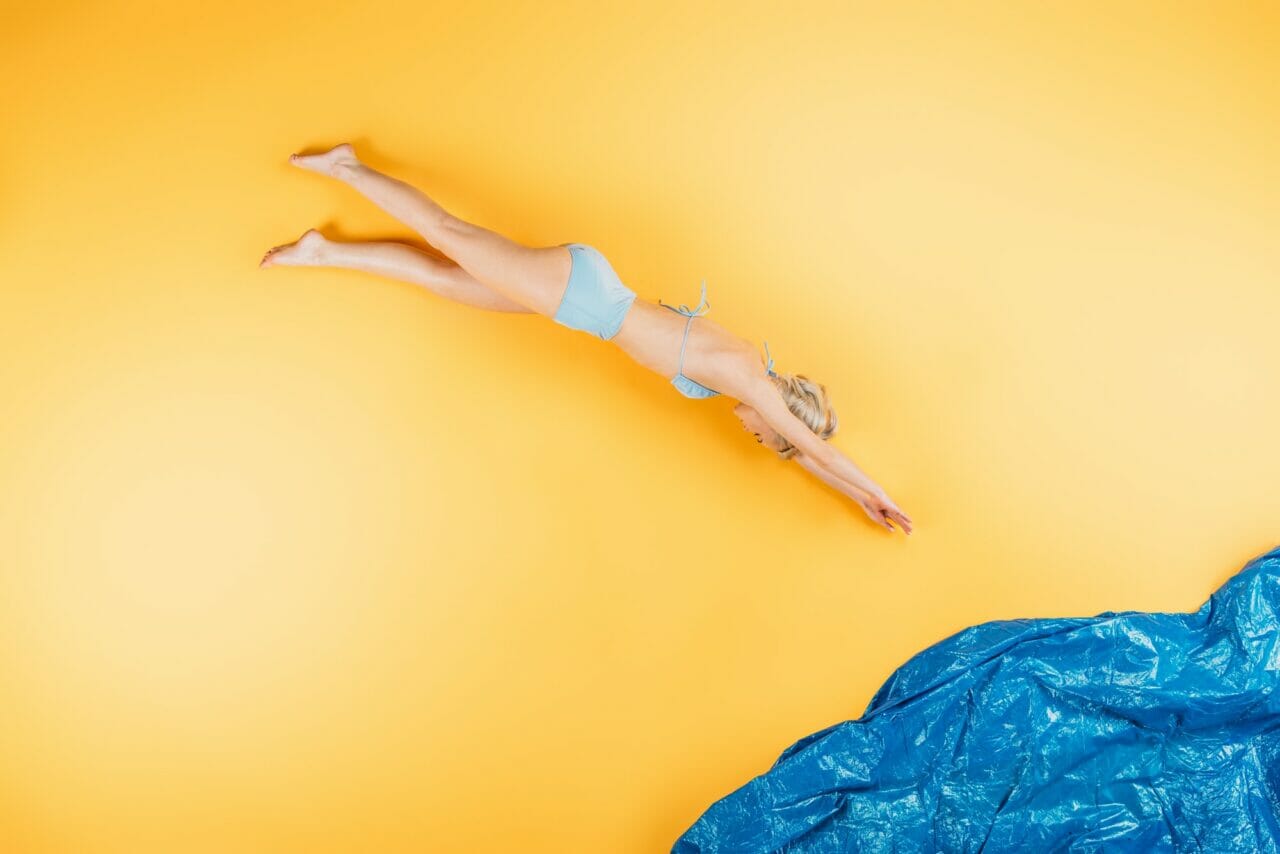 young woman in swimsuit diving in imagine sea on yellow