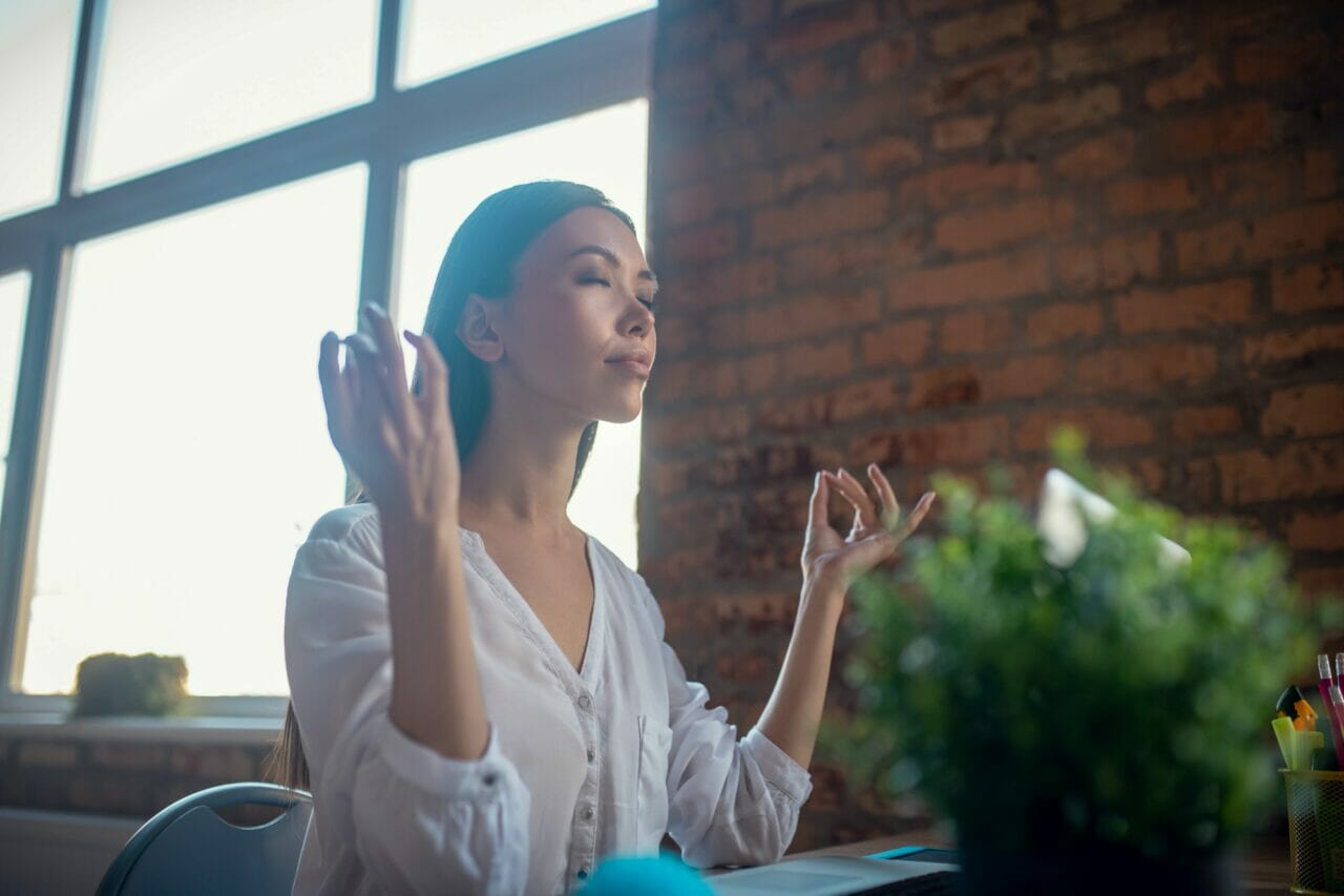 beautiful calm young woman meditating at work