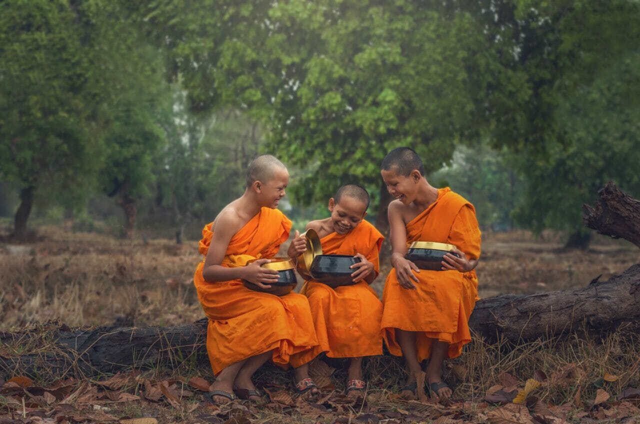 three neophyte monk are talking and holding the monk s alms bowl on the timber of the tree