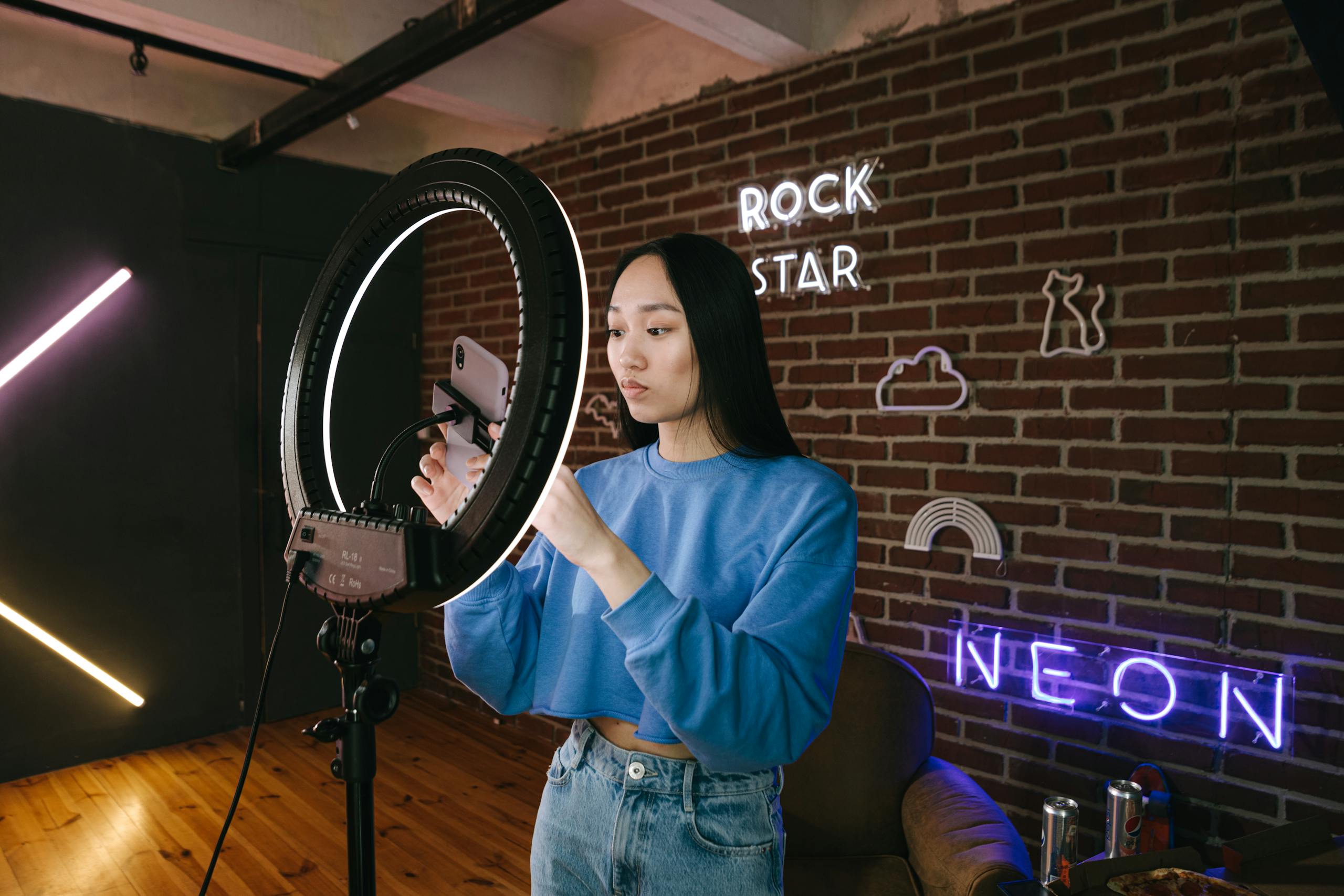 asian woman influencer sets up a ring light in a neon lit room for content creation. 7676403 scaled